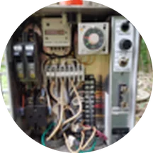 Open system control panel mounted on a wooden post, showing breakers, a timer and wiring